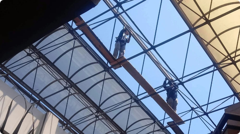 A construction worker wearing a safety harness on a roof, demonstrating safe work at height practices